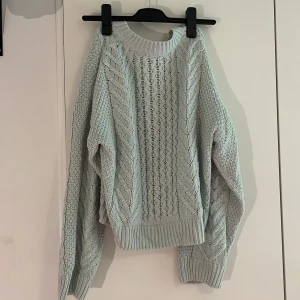 Stickad tröja - Säljer en ljusblå stickad tröja med snyggt flätmönster både fram och på ärmarna. Har missfärgning på ena armen se bild två och tre 