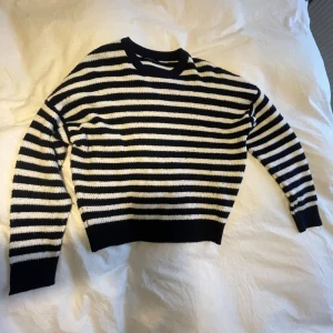 Randig stickad tröja - Jag säljer en randig stickad tröja, i färgerna svart och vit. Den är från Alcott. Den är sparsamt använd. Nypris 450kr.