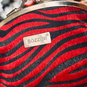 Fin vintage-portmonä från Bozzini! - Fin vintage-portmonä i zebramönster och flera fack från Bozzini. Mått: 12 x 16 cm. I mycket fint skick.  Bozzini grundades i Sverige och är ett svenskt varumärke som står för kvalitet, variation och stilfull design. De designar och producerar högkvalitativa produkter och deras engagemang för kvalitet och känsla för stilfulla detaljer garanterar att alla dess produkter är byggda för att kunna användas länge, både sett till hållbarhet och stil!