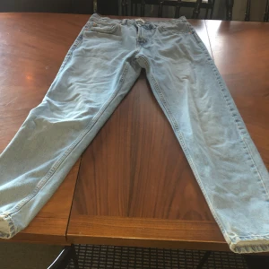 Ljusblå jeansbyxor från 157 - Säljer ett par klassiska ljusblå jeansbyxor från 157. De har en rak passform, fem fickor och stängs med dragkedja och knapp. Perfekta för dig som gillar en tidlös och enkel stil.