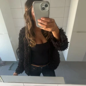 Svart fluffig jacka - Säljer en svart fluffig jacka eller kofta från Nelly som är jätte fin. Finns inte kvar längre i lager. Perfekt inför sommaren när det bli lite kallare!