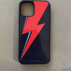 iPhone 12 Skal - Bowie Blixt - Säljer då den inte kommer till användning plus att jag har fått en ny mobil. Den har inga defekter eller slitage då den har bara legat i mitt nattduksbord. 
