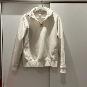 Vit halvzip sweatshirt från Zara  - Säljer en stilren vit sweatshirt från Zara med halv dragkedja i halsen. Tröjan har lång ärm, hög krage och är tillverkad i mjuk bomull. Perfekt för en avslappnad och clean look.