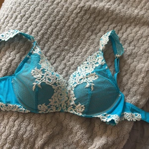 Turkos spets-bh från Intimissimi - Säljer en turkos bh från Intimissimi med vacker vit spetsdetalj över kuporna och längs kanterna. Köpte och klippte bort lappen men sedan när jag testade så var den för liten🥲. Bh:n har justerbara axelband och en feminin design som verkligen sticker ut. 