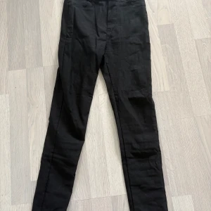 Svarta tighta byxor med hög midja - Svarta byxor med tight passform och hög midja. Byxorna har två knappar framtill och klassiska fickor bak. Perfekta till vardags och enkla att matcha med olika toppar.