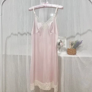 Ljusrosa nattlinne med spetsdetaljer - Säljer en ljusrosa nattlinne med smala axelband och vacker spets vid byst och nederkant. Klänningen har en mjuk, glansig yta och en feminin siluett. Är delvis transparent (se bild 4).