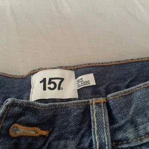 Blå jeans från 157 New Classic - Ett par klassiska blå jeans från 157 New Classic med raka ben och normal passform. Jeansen har dragkedja och knapp framtill samt klassiska fickor både fram och bak. Perfekta för en avslappnad stil.