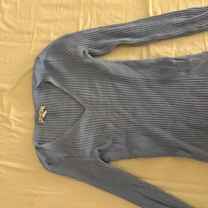 Ljusblå ribbad långärmad topp - Säljer en ljusblå ribbad långärmad topp från Chiquelle. Tröjan har v-ringning och är figurnära i modellen, perfekt att styla till jeans eller kjol. Supermjuk och stretchig i materialet.