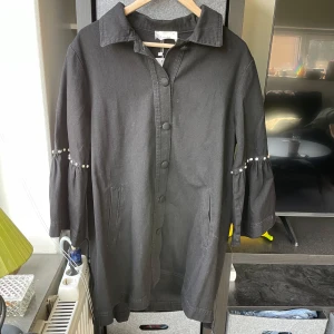 Svart kappa med pärldetaljer från Touché - Nu med prislapp! Säljer en svart kappa från Touché med pärldetaljer på ärmarna. Jackan har korta ärmar!