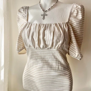 Rabdig topp med puffärmar - Supersöt topp med beige och vita ränder, puffiga korta ärmar och rynkad byst. Toppen har en fyrkantig urringning och är i nyskick ❣️