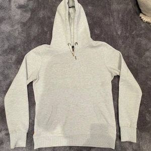 Ljusgrå hoodie från Superdry - Säljer en sjukt snygg ljusgrå hoodie från Superdry. Skicket är otroligt bra, som nytt. Passar perfekt nu till våren och sommaren och den är lätt att matcha till! Vid fler frågor är det bara att höra av er!