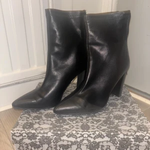 Svarta boots med klack och spetsig tå - Säljer ett par svarta boots i skinnimitation med hög klack och spetsig tå. Skorna har dragkedja på insidan och en stilren design som passar till många outfits. Perfekta för dig som vill ha en edgy och trendig look.