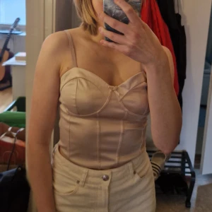 Ljusrosa satin korsetlikande topp från H&M - Säljer en ljusrosa satin topp från H&M Divided. Den har markerade kupor och dekorativ söm framtill. Perfekt att styla till olika festliga looks! På sista bilden vid tummen syns en liten skavank troligtvis från ett kardborreband, därav priset. Skriv vid frågor!✨️ Samfraktar gärna så kika in mina andra inlägg!✨️