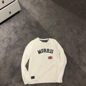 Vit stickad tröja från Morris - Säljer en vit stickad tröja från Morris med blå text och brittisk flagga framtill. Storlek S men passar M också!