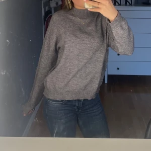 Grå stickad tröja - Säljer en enkel och stilren grå stickad tröja med rund halsringning. Tröjan har långa ärmar och ribbade muddar vid ärmslut och nederkant. Perfekt för lager-på-lager och passar till det mesta.
