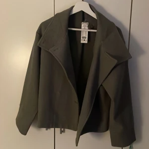 Grå kort jacka från Gina Tricot - Säljer en helt oanvänd vår/höst jacka ifrån Gina Tricot, säljer den för att den inte kändes som min stil, köptes förra hösten❣️kan diskutera pris om de är rimligt!