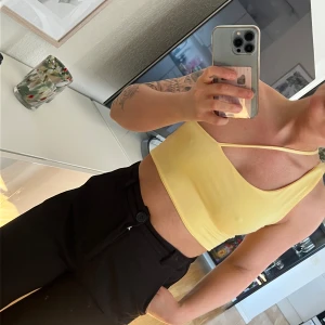 Gul croppad tubtopp med smala axelband - Snygg gul croppad tubtopp med smala axelband och enkel design. Perfekt för varma dagar och enkel att matcha med olika outfits.