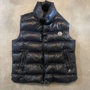 Moncler Tibet down  - ‼️Västen är inköpt från mig personligen från GARMSMARKET, kvitto finns bara att höra av er så skickar jag bild‼️ Säljer en marinblå dunväst från Moncler med hög krage och två snedställda fickor med dragkedja. Perfekt för lager-på-lager under kyliga dagar.