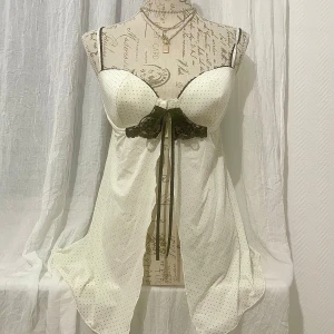 Vit prickig nattlinne från Esmara - Säljer ett elegant vitt nattlinne från Esmara med svarta prickar och spetsdetaljer. Den har smala axelband, en dekorativ snörning framtill och en slits i mitten. Perfekt i kombination med en minikjol för att ge en y2k-look. STORLEK: 80C som passar byst 97-99cm.