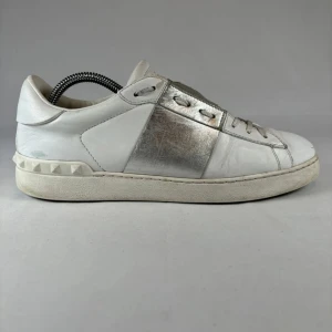 Valentino Open sneakers i vitt och silver - Säljer ett par Valentino Open sneakers i vitt skinn med silverfärgade detaljer på sidorna. Skorna har klassisk snörning och ikoniska nitar på hälen. Perfekta för dig som gillar lyxiga och stilrena sneakers.