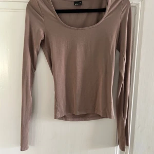 Beige/brun långärmad topp från Gina Tricot - Säljer en enkel och stilren beige långärmad topp från Gina Tricot. Toppen har rundad urringning och är tillverkad i ett mjukt bomullsmaterial. Perfekt att matcha med jeans eller kjol.