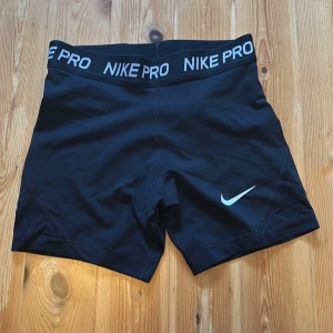 Nike Pro svarta träningsshorts - Svarta Nike Pro shorts i tight passform med bred resår i midjan där det står NIKE PRO. Perfekta för träning och sport. Gjorda i stretchigt syntetmaterial som andas och sitter skönt på kroppen. Storlek L (obs barnstorlek L) alltså en större barnstorlek skulle gissa på 158/164. Jag skukle säga att det är som en XXS vuxenstorlek. Shortsen är i jättefint skick. KAN ABSOLUT GÅ NER I PRIS VID SNABB AFFÄR ELLER BUNDLE!