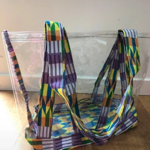 Färgglad transparent shoppingväska beachbag oanvänd - Stor och rymlig shoppingväska eller beachbag. Väskans band har unikt mönster i västafrikanskt tyg och mjuk plast som skydd för fuktiga handdukar.  Tillverkad i Senegal, oanvänd. Mått: längd 30cm, bredd 15cm och höjd 28cm.