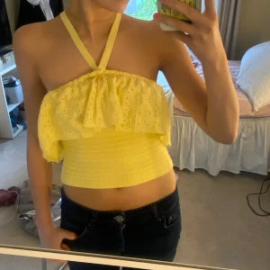 Gul halterneck topp från Zara - Supersöt gul halterneck topp från Zara med broderade hål och volang upptill. Toppen är använd en gång och är i jätte bra skick.