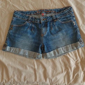 Jeanse shorts - Ett par lågmidjade jeanse short med ett super snyggt mönster på fickorna från Jane Norman i stl Xs. 