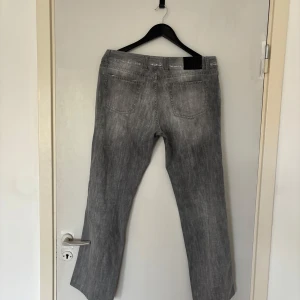 Grå jeans från Zegna i rak modell - Snygga grå jeans från Zegna med klassisk femficksdesign och raka ben. Jeansen har en diskret tvättad look, silverfärgade detaljer och svart patch bak i midjan. Perfekta för dig som gillar stilrena och tidlösa jeans med modern känsla.