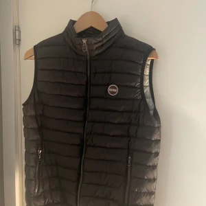 Mörkblå dunväst från Colmar storlek XS - Snygg mörkblå dunväst från Colmar med quiltad design och hög krage. Den passar perfekt för dig som är mellan 160-170. Perfekt att slänga över den på  en hoodie eller tröja när det är kyligt ute.