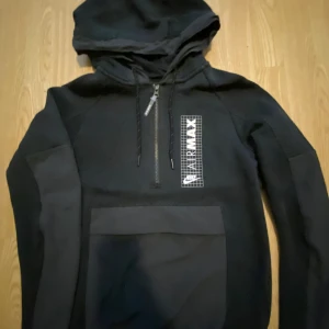 Svart Nike Air Max hoodie med half zip - Svart hoodie från Nike Air Max med stor magficka, huva med snörning och half zip-dragkedja. Reflex snören