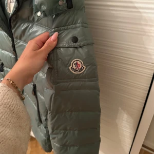 Moncler jacka  - Moncler jacka i storleken 12y, (passar mig som är Xxs/xs i storleken. Super fin grön unik.. 💕jackan är självklart äkta och vid mer information om äkthetsbevis hör av dig !  Jackan är i toppen skick med en avtagbar luva. Sista bilden så ser man att lappen lossnat på sömmen längst ner men sitter fortfarande kvar.Djur och rökfritt hem💕Jackan är köpt på vesitaire collective 🫶🏼är i ett fint skick, har användes under en vinter! Jackan kommer att tvättas& puffas till innan frakt.Säljes i befintlig skick