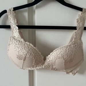 Beige spetsig bh - Superfin beige bh med breda axelband och vacker spetsdetalj över hela framsidan och banden. När jag köpte den stod det storlek 75B men storlekarna är annorlunda den är mycket mindre än en B kupa. Passar nog bäst för någon med A kupa.