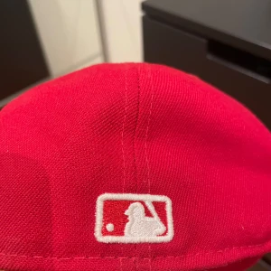 Röd LA Dodgers keps New Era 59FIFTY - Snygg röd LA Dodgers keps från New Era, modell 59FIFTY. Klassisk basebollstil med broderad LA-logga framtill och MLB-logga bak. Kepsen är i fast modell med platt skärm och broderade ventilationshål. Perfekt för dig som gillar sportig streetstyle. (Nypris 500kr och den är helt oanvänd)