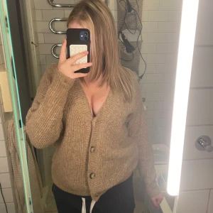 Beige stickad kofta med knappar - Mysig beige stickad kofta med v-ringning och stora knappar framtill. tröjan är barn storlek 13-14 år men passar S-L Aldrig använt men lite nopprig 