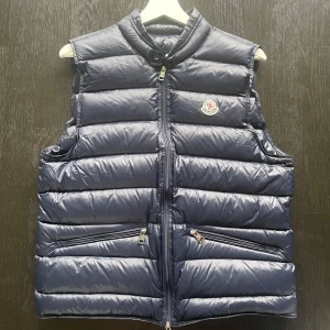 Mörkblå dunväst från Moncler -  Kontakta mig kan jag skicka videos på västen. Storleken är 2. Tagga finns i märket. Snygg mörkblå dunväst från Moncler med quiltad design och hög krage. Västen har två dragkedjefickor framtill, Moncler-logga på bröstet och stängs med dragkedja. Perfekt för lager-på-lager och ger en clean, sportig look.