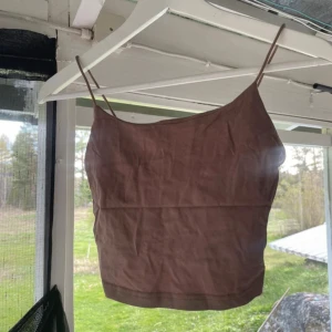 Brun linnetopp från SHEIN XS - Säljer en brun croppad linnetopp från SHEIN i storlek XS. Toppen har tunna axelband och är figurnära med enkel design, perfekt till jeans eller kjol. Materialet är mjukt och lätt, vilket gör den skön att bära under varma dagar.