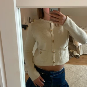 Krämvit stickad cardigan från Zara - Superfin beige/krämvit stickad cardigan från Zara med guldiga knappar och två fickor framtill. Jackan är croppad och har lång ärm, perfekt för lager på lager. Enkel och stilren design som passar till det mesta. Lite sliten vid ett knapphål, men annars bra skick. Storlek M men passar mig som vanligtvis är XS/S💕