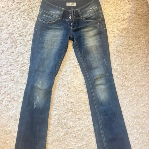 Mörkblå jeans med slitningar TRE Denim - Snygga mörkblå jeans från TRE Denim med slitna detaljer och ljusare partier framtill. Låg midja. Sitter ganska löst i midjan