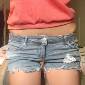 Grå jeansshorts från ONLY - Säljer ett par sjukt snygga grå jeansshorts från ONLY med låg midja och slitna detaljer🤗 Shortsen har fransig kant nertill, klassiska fem fickor och dragkedja med knapp. Perfekta för sommaren och ger en cool, avslappnad vibe.☀️😎 Tillverkad i ett strechigt meterial!! Öppen att diskutera pris!💕