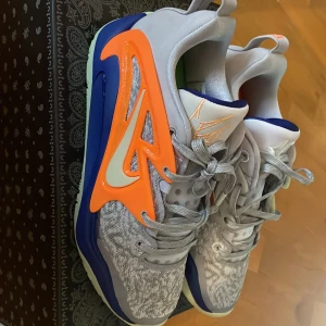 Nike KD  15 X  basket skor grå/orange/mintgrön  - Nike KD 15 basket skor  med gråmelerad mesh, färgstarka detaljer i orange, mintgrönt och blått. Snyggt KD-märke på plösen och unik design på sidorna. Skorna har snörning och platt sula, perfekt för dig som gillar basketinspirerad stil. Dom lyser i mörket får sådana bilder skriv i chatt 