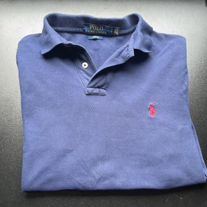 Marinblå pikétröja från Ralph Lauren - Snygg marinblå pikétröja från Ralph Lauren i slim fit-modell. Ganska använd men i fint skick! Priset kan diskuteras och det är bara att höra av sig om man vill ha fler bilder mm😁💛🌟