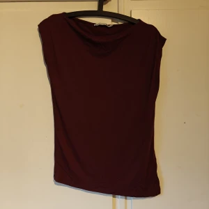 Mörkröd ärmlös topp från 157 - Enkel och stilren mörkröd topp från 157. Modellen är ärmlös med rund halsringning och rak passform. Perfekt att matcha med jeans eller kjol för en clean look. Tunt och mjukt material som känns skönt mot huden.