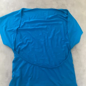 Blå kortärmad topp  - En enkel och stilren blå topp med korta ärmar och rund hals. Öppen rygg där bak 