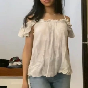 Vit offshoulder blus - Säljer en supersöt vit blus från Gina Tricot i storlek 34. Offshoulder-modell med volangdetaljer längs halsringningen och ärmarna. Tunt, luftigt tyg med diskret struktur och lätt mönster. Perfekt för varma dagar när du vill ha en romantisk och chill vibe.