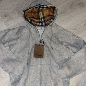 Burberry Hoodie  - Säljer Min Vintage Burberry Gråa Hoodie som är gjord på burberrys ”tysta” sätt. Det är alltså utan riddar loggan vid bröstet. Då dem inte fokuserat på märket där framme så har dem gjort felfria stygn och perfekt linje vid checkmark i luvan!‼️ Storlek: M, Men passar också folk som bär S. Hör av er vid minsta lilla fundering, priset är EJ hugget i sten och går att diskuteras!🪨✅🎉❤️