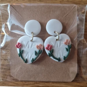 Polymer clay örhängen  - Ett par unika örhängen med hjärtform och texten "Mama". Längd 4cm Bredd 2,5cm..