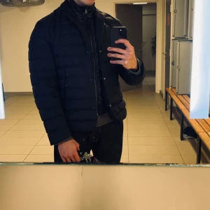 J.Lindeberg Navy Blouse Jacka - Säljer en lyxig navy pufferjacka med dragkedja och knappar. Ser ut som en kavaj samtidigt, skitsnygg. Från JLindeberg, från 2023 kollektion säljs ej längre, nypris var 7000kr.