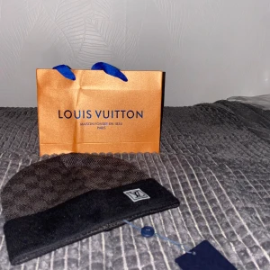 svart rutig mössa - Exklusiv svart mössa från  med klassiskt rutigt mönster och uppvikt kant. Mössan har en diskret  framtill och är tillverkad i mjukt material som håller dig varm och snygg. Perfekt accessoar för dig som gillar lyxiga detaljer.